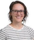 Headshot: woman in a black and white striped shirt and glasses smiling at the camera