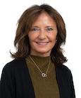 Headshot: Dark haired woman in green turtleneck with black jacket smiling at camera